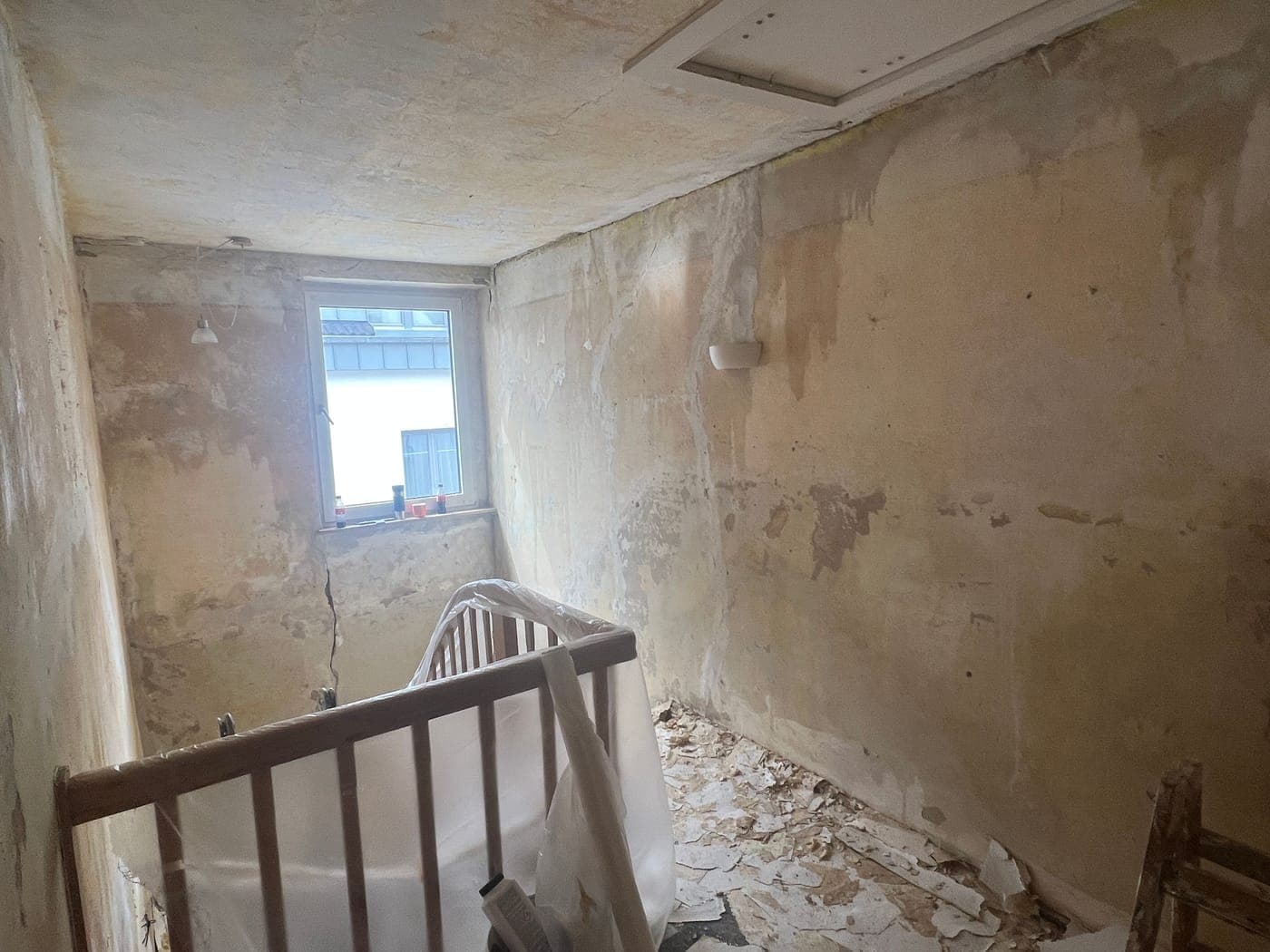 Treppenhaus mit abgeschlagenem Putz und beschädigten Wänden vor der Sanierung